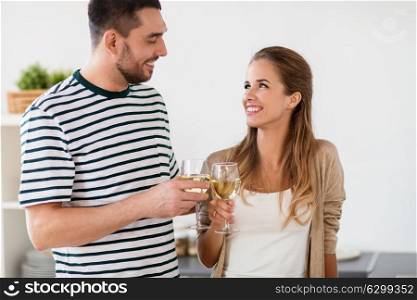 celebration, people and leisure concept - happy couple drinking wine and clinking glasses at home. happy couple drinking wine at home
