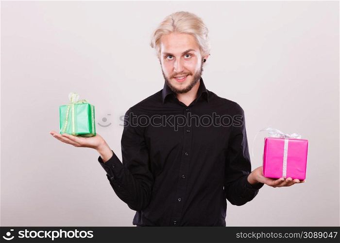 Celebration, special occasion, holidays concept. Trendy young man holding presents pink and green gift boxes in hands. man holding two gift boxes in hands