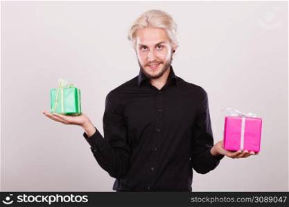 Celebration, special occasion, holidays concept. Trendy young man holding presents pink and green gift boxes in hands. man holding two gift boxes in hands