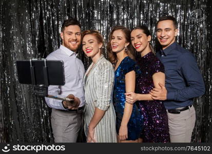 celebration, technology and holiday concept - happy friends taking selfie by smartphone at party. happy friends taking selfie by smartphone at party