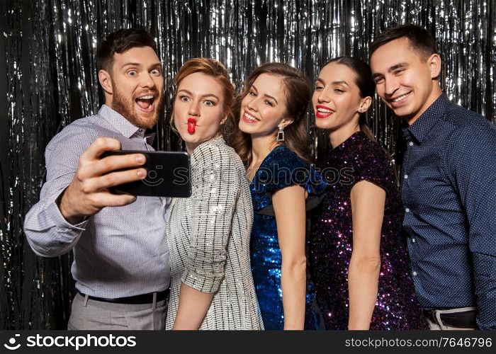 celebration, technology and holiday concept - happy friends taking selfie by smartphone at party. happy friends taking selfie by smartphone at party