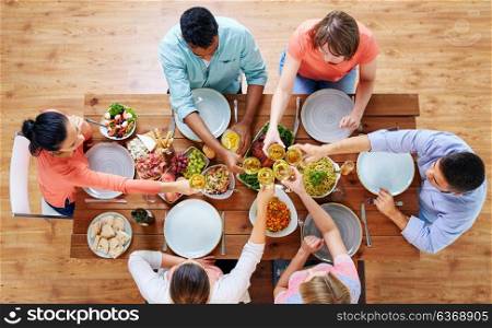 celebration, thanksgiving day, eating and holidays concept - group of people having dinner at table with food and clinking wine glasses. people having dinner and clinking wine glasses