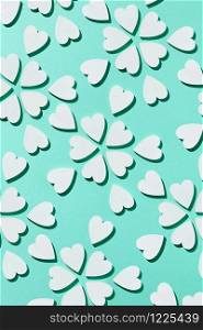 Celebratory Valentine&rsquo;s card with creative flowers pattern handmade from plaster small hearts on a pastel turquoise background with hard shadows, copy space. Flat lay. Congratulation card.. Flowering pattern made from plaster hearts with shadows.