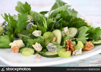 Celery leaves and stalks salad with fresh cucumber slices, blue cheese, crushed nuts.