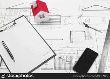 cellphone clipboard with small house model blueprint