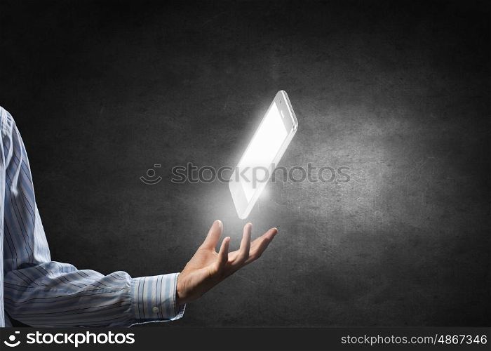 Cellphone in palm. Businessman holding in hand glowing mobile phone on dark background