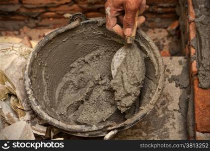 Cement mortar with trowel in worker hand