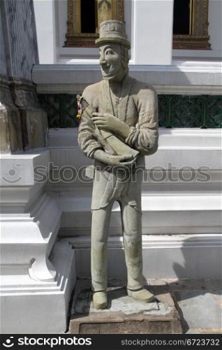 Cement sculpture of man near white temple in wat Suthat, Bangkok, Thailand