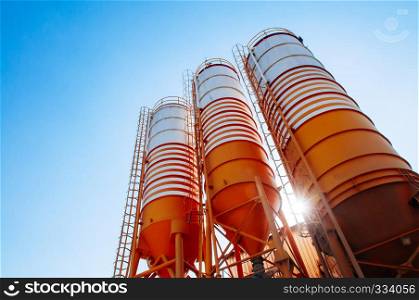 Cement silos of Cement batching plant factory against afternoon sun with clear blue sky