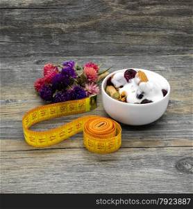 Centimeter and granola with yogurt on rustic wooden background.