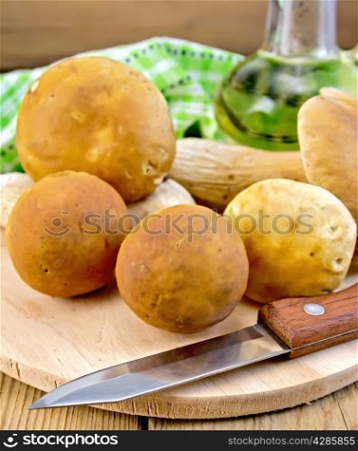 Ceps, knife, decanter with vegetable oil, napkin on the background of wooden boards