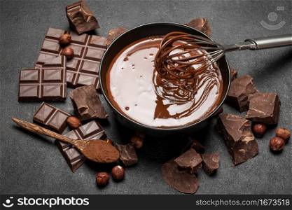 ceramic bowl of chocolate cream or melted chocolate and pieces of chocolate on dark concrete background or table. ceramic bowl of chocolate cream or melted chocolate and pieces of chocolate on dark concrete background