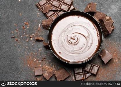 ceramic bowl of chocolate cream or melted chocolate and pieces of chocolate isolated on dark concrete background or table. ceramic bowl of chocolate cream or melted chocolate and pieces of chocolate isolated on dark concrete background