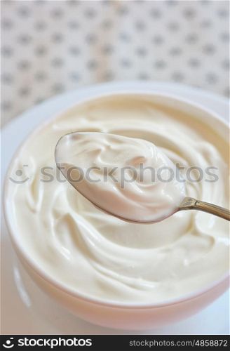 Ceramic bowl of white yoghurt in spoon