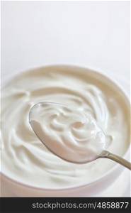 Ceramic bowl of white yogurt in spoon
