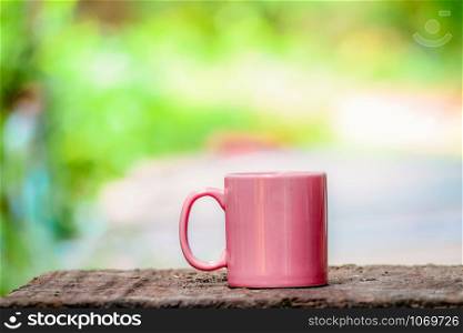 Ceramic coffee cup on old wood with summer nature green and yellow background