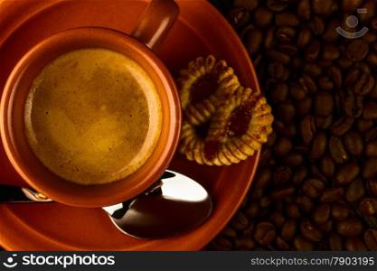 ceramic cup of coffee, sweet and coffee beans on wooden background