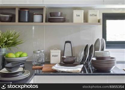 Ceramic dishes and bowls on the counter and shelf in the modern kitchen