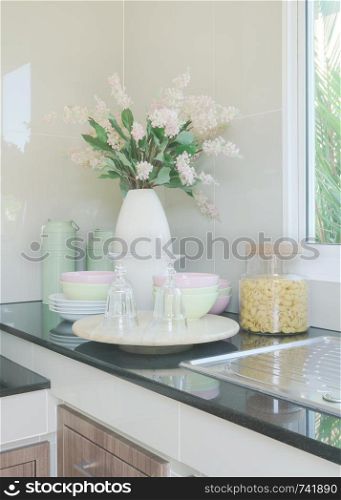 Ceramic kitchenware and flower vase on black counter top in the kitchen