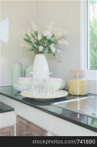 Ceramic kitchenware and flower vase on black counter top in the kitchen