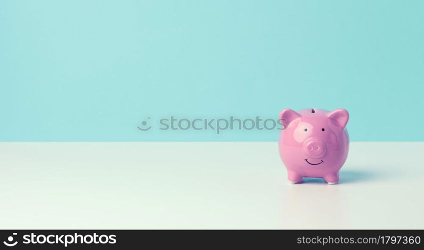 ceramic pink piggy bank on a blue background. Concept of increasing income from bank accounts, savings, copy space