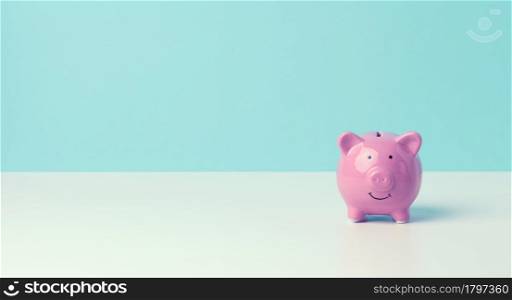 ceramic pink piggy bank on a blue background. Concept of increasing income from bank accounts, savings, copy space