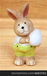Ceramic rabbit with a egg on a wooden background