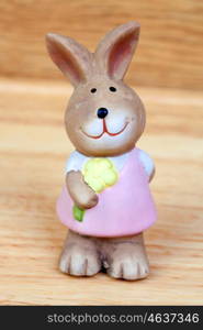 Ceramic rabbit with a flower on a wooden background