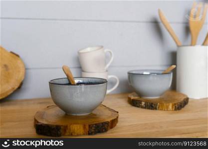 Ceramic tureen with a wooden spoon on a sawn wooden stand in the kitchen in the Scandinavian style