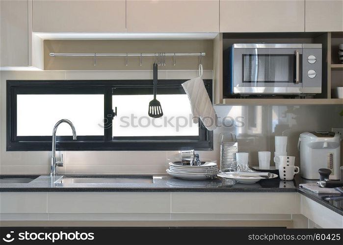 Ceramic ware and utensils setting up next to sink in modern kitchen