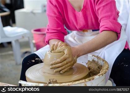 Ceramic working process with clay potter's wheel, close up. The woman is making pottery in studio.