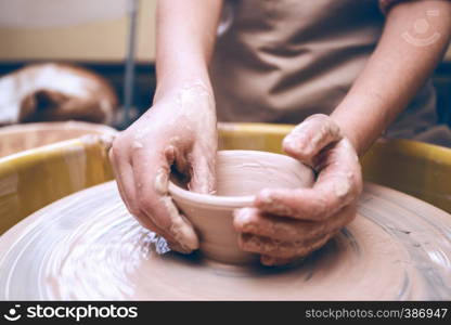 ceramic workshop - the girl makes a pot of clay on a potter's wheel. hands closeup