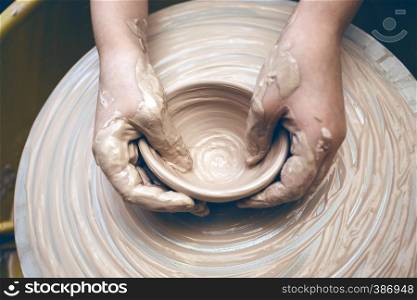 ceramic workshop - the girl makes a pot of clay on a potter's wheel. hands closeup