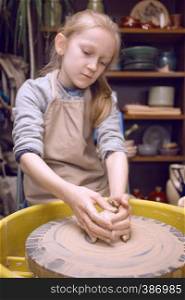 ceramic workshop - the girl makes a pot of clay on a potter's wheel