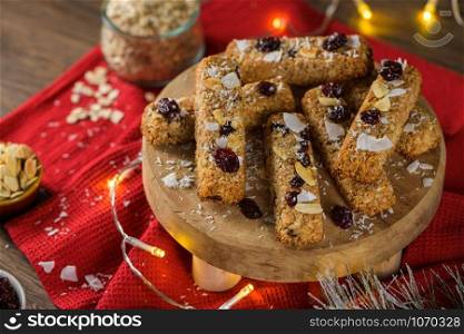 Cereal bars with almonds, coconut and cranberries on a Christmas season table decorated with lights.