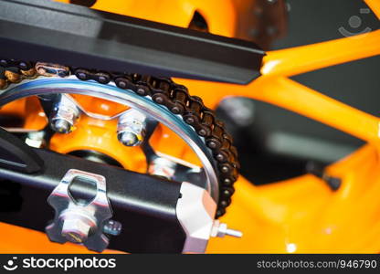 Chain and gear wheel of new yellow motocycle close up