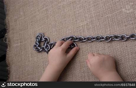 Chain made of metal in hand on canvas background