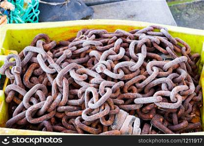 chain of a fishing boat on a pontoon in the morning covered with frost in a yellow crate