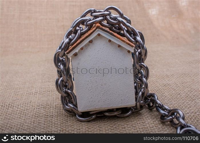 Chain wrapped around a model house on a brown background