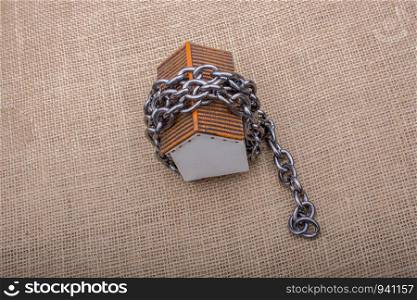 Chain wrapped around a model house on a brown background