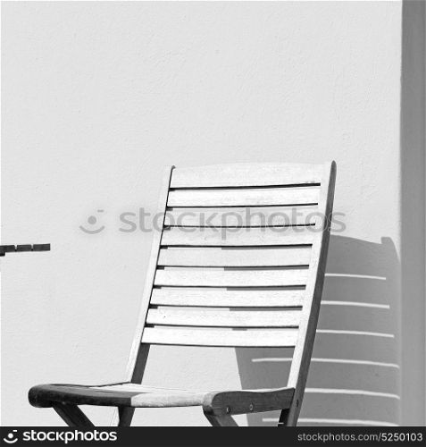 chair and stone pavement in the greece island of paros old bench near a brick antique wall