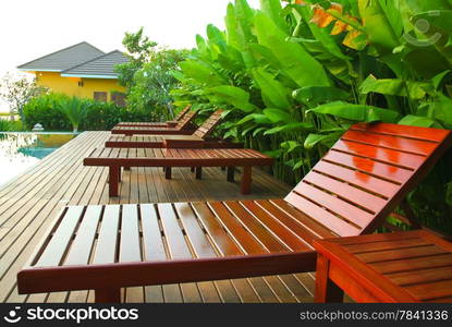 chair and swimming pool surrounded by tropical plants