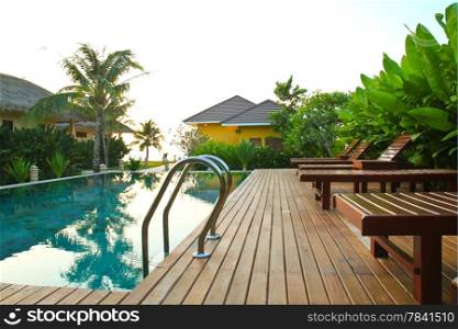 chair and swimming pool surrounded by tropical plants