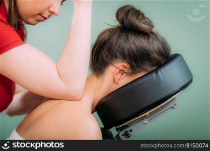 Chair Massage in the Office. Female sitting in her office on a portable massage chair. Therapist massaging her neck for stress relief