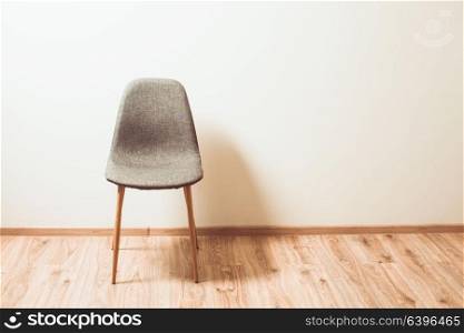 Chair stands near the wall in the empty room. Chair in the empty room