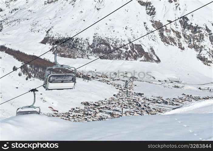 Chairlifts running above a mountain village - shot in Livigno, Italian Alps
