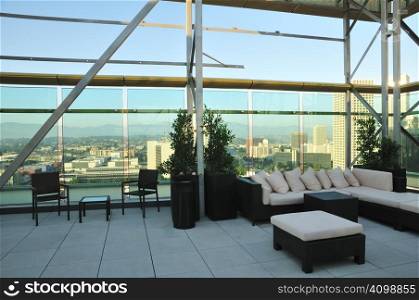 Chairs and a couch provide a place to enjoy the downtown sunset from a highrise rooftop