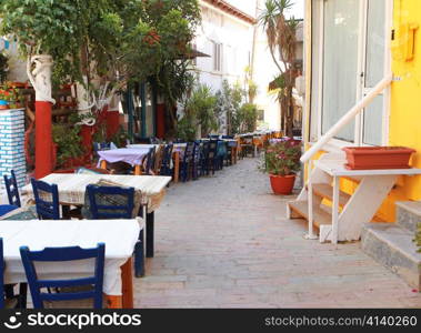 Chairs and tables belonging to a taverna line a popular pedestrian street in Agia Galini, Crete, Greece,