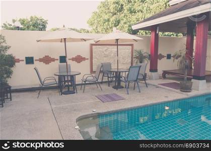 Chairs and umbrella swimming pool. Vintage tone.