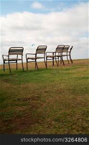 Chairs in field while parachute flying in sky